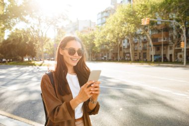 Görüntü şaşırtıcı mutlu güzel kadının cep telefonunuzun ve açık havada yürüyüş.