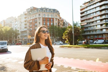 Görüntü şaşırtıcı mutlu güzel kadının açık havada tutan yürüyüş dizüstü bilgisayar.