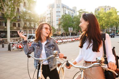 İki genç güzel kadın arkadaşlar açık havada Bisiklet Park ile görüntü.