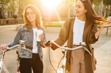 İki genç duygusal kadın arkadaşlar açık havada Bisiklet Park ile şaşırtıcı resmi.