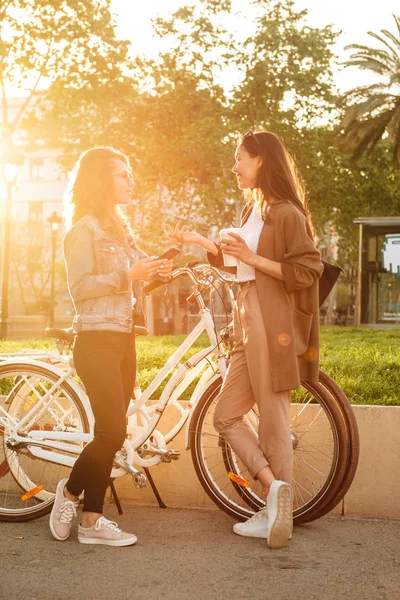 Bilden Två Unga Vackra Kvinnor Vänner Utomhus Med Cyklar Parken — Stockfoto