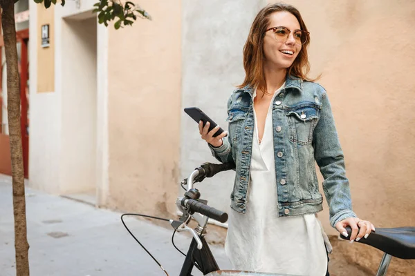 Bilden Fantastisk Glad Vacker Kvinna Promenader Utomhus Cykel Med Mobiltelefon — Stockfoto