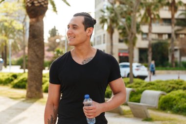 Açık havada su şişe ile yürüyen adam neşeli genç güçlü görüntü spor.