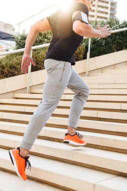 Yakışıklı genç güçlü spor adam açık havada merdivenlerinde görüntü kırpılmış.