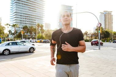 Yakışıklı genç güçlü görüntü açık havada müzik dinleme koşan adam spor.