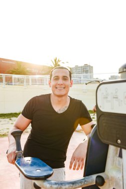 Fotoğraf mutlu yakışıklı genç güçlü adam açık havada yapmak egzersizleri spor. Görünümlü kamera.