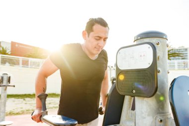 Fotoğraf konsantre yakışıklı genç güçlü adam açık havada yapmak egzersizleri spor.