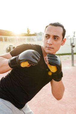 Fotoğraf genç konsantre güçlü spor erkek boxer açık havada yapmak egzersizleri eldiven.