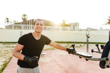 Fotoğraf genç mutlu güçlü spor erkek boxer açık havada egzersiz eldiven içinde olun. Görünümlü kamera.