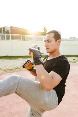 Görüntü genç konsantre güçlü spor erkek boxer açık havada yapmak egzersizleri eldiven.