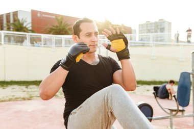 Fotoğraf genç konsantre güçlü spor erkek boxer açık havada yapmak egzersizleri eldiven.