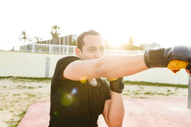 Görüntü genç konsantre güçlü spor erkek boxer açık havada yapmak egzersizleri eldiven.