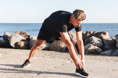 Deniz kenarında yakışıklı sporcu germe yapmak egzersizleri
