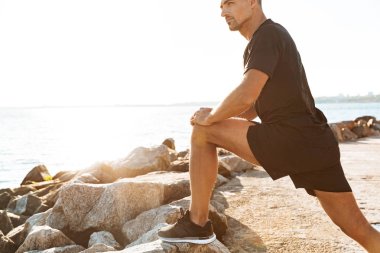 Sabah deniz kenarında germe egzersizleri yapıyor odaklı sporcu görüntü kırpılmış