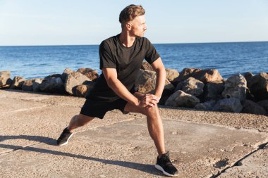 Deniz kenarında güçlü sporcu germe yapmak egzersizleri