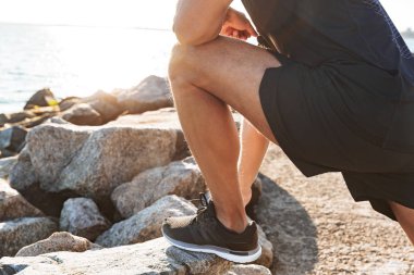 Sabah deniz kenarında germe egzersizleri yapıyor bir sporcu görüntü kırpılmış