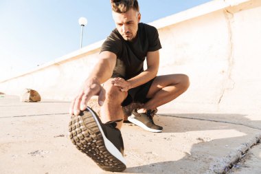 Sabah deniz kenarında germe egzersizleri yapıyor odaklı bir sporcu portresi