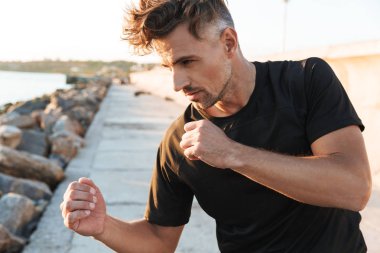 Konsantre sporcu boxer fotoğrafını erken sabah sahilde açık havada spor boks egzersizleri yapmak.
