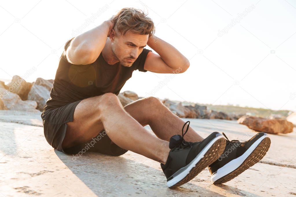 Portrait of a concentrated sportsman doing abs exercises outdoors