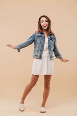 Bej renkli arka plan üzerinde izole ayakta iken poz yaz giysileri neşeli bir genç kızı tam uzunlukta portresi