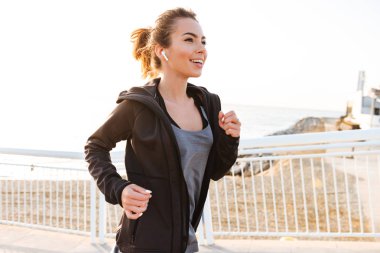 Çekici genç görüntü açık havada sokak dinleme müzik kulaklık ile çalışan kadın spor.