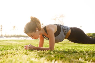 Plank egzersizleri çimenlerin üzerinde açık havada spor yapmak imge-in genç fitness kadın.
