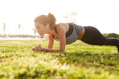 Plank egzersizleri çimenlerin üzerinde açık havada spor yapmak imge-in genç fitness kadın.