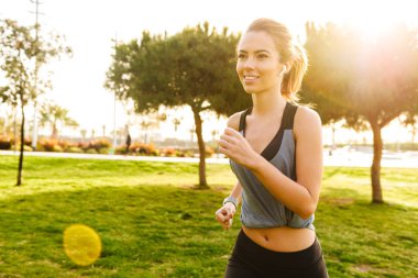 Güzel genç fotoğrafı açık havada park müzik dinleme çimenlerde earphones ile çalışan Bayan spor.