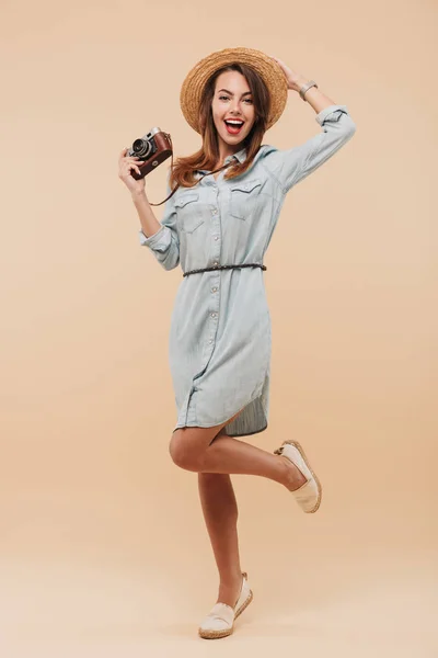一个快乐的年轻女孩的全长肖像持有照片相机 而站在米色背景隔离 — 图库照片