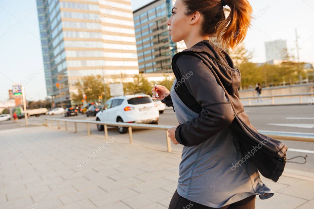 Back view photo of amazing young sports woman running outdoors on the street.