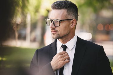 Başarılı bir iş adamı portresi dışında ve kravatını dokunmadan takım elbise yürüme giyinmiş