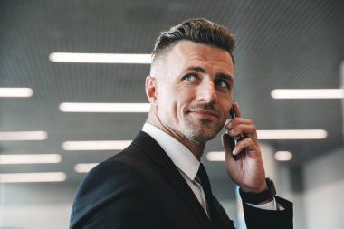 Olgun işadamı Havaalanı lobide duran cep telefonu konuşurken gülümseyen