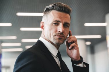 Havaalanı lobide duran cep telefonu konuşurken kendinden emin olgun işadamı