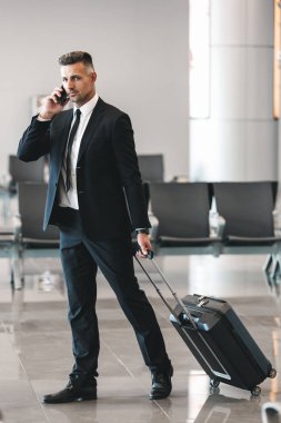 Bavulla Havaalanı Lobide yürürken cep telefonu üzerinde konuşurken yakışıklı olgun işadamı