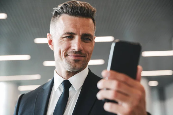 Smiling Mature Businessman Looking Mobile Phone While Standing Airport Lobby — Stock Photo, Image