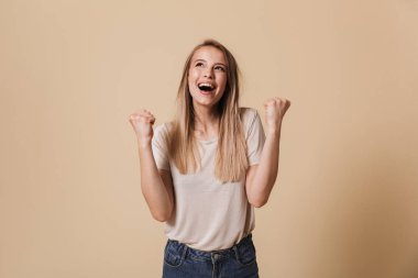 Bej renkli arka plan üzerinde izole başarı kutluyor neşeli bir casual kız portresi