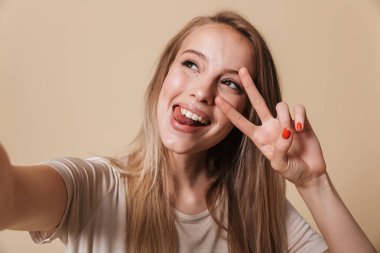 Bej renkli arka plan üzerinde izole uzanmış eller ile bir selfie alarak mutlu bir genç kız portresi