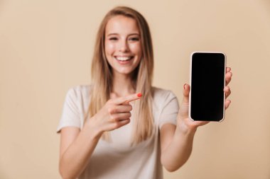 Boş ekran cep telefonu bej renkli arka plan üzerinde izole, oldukça casual kız işaret eden bir parmağa portresi