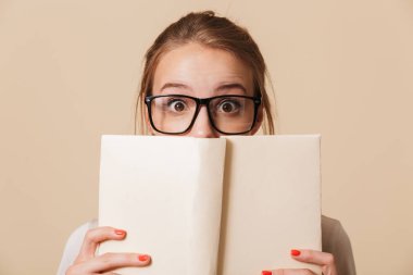 Bej renkli arka plan üzerinde izole yüzü adlı kitap tutan Eyewear bir genç kız portresi