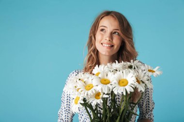 Buket çiçek tutan ve mavi arka plan üzerinde seyir içinde mutlu sarışın kadın