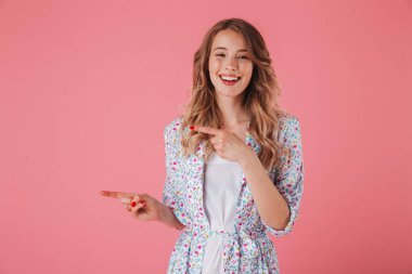 Yaz elbise işaret parmağı üzerinde pembe arka plan izole bir heyecanlı genç kadın portresi