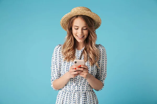 微笑的金发女郎在礼服和帽子写信息在智能手机以上的蓝色背景 — 图库照片