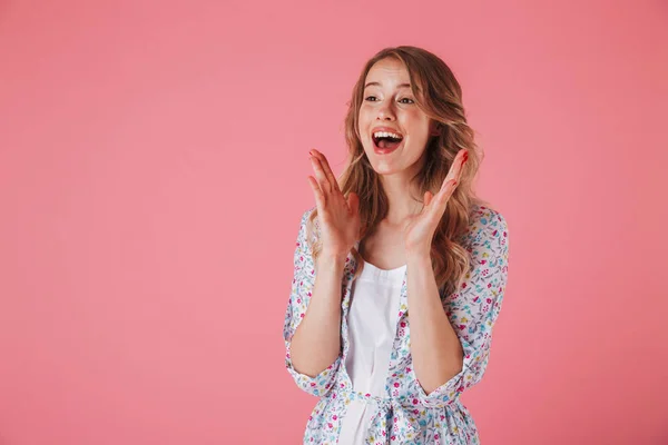 一个兴奋的年轻女子在夏季礼服的肖像看着在粉红色背景孤立的复制空间 — 图库照片