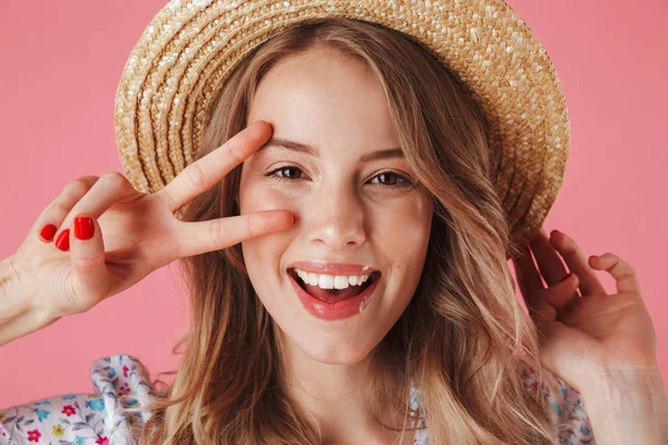 关闭在夏季礼服和草帽显示和平姿态隔离粉红色背景的年轻女子的肖像 — 图库照片