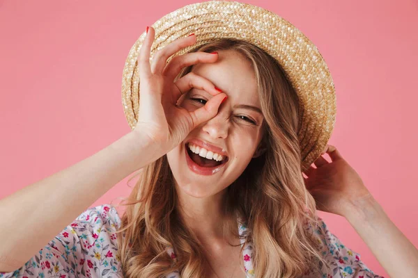 关闭在夏季礼服和草帽显示一个快乐的年轻女子的肖像在粉红色背景下确定的手势隔离 — 图库照片