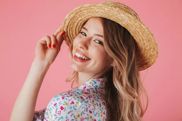 夏のドレスと麦わら帽子とピンクの背景に分離カメラ目線 ポーズでかなり若い女性の肖像画間近します — ストック写真