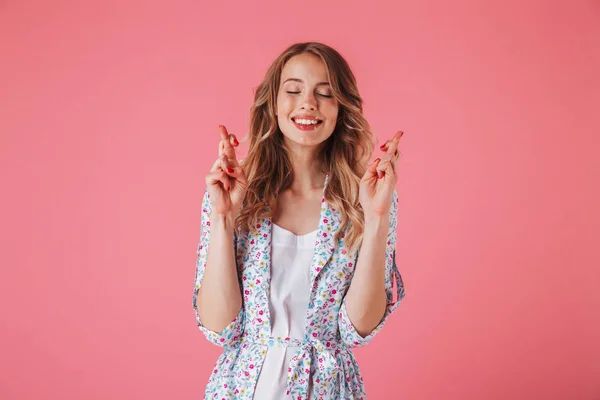 ピンク背景に分離された幸運を祈って開催の夏のドレスで幸せな若い女の肖像 — ストック写真