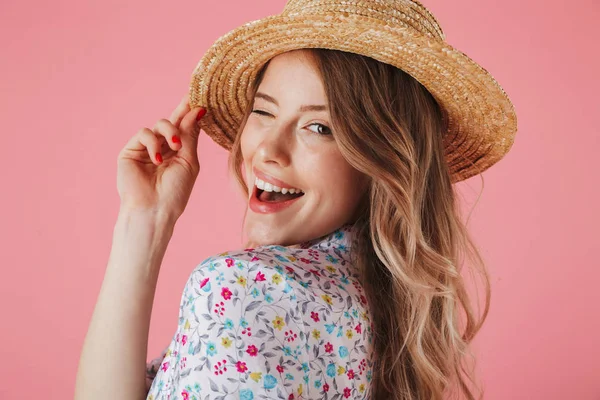 夏のドレスと麦わら帽子とピンクの背景に分離カメラ目線 ポーズで陽気な若い女性の肖像画間近します — ストック写真