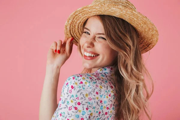 夏のドレスと麦わら帽子とピンクの背景に分離カメラ目線 ポーズで笑っている若い女性の肖像画間近します — ストック写真