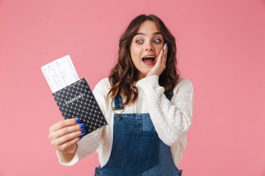 Pasaport bilet üzerinde pembe arka plan izole uçan ile bir neşeli genç kız portresi